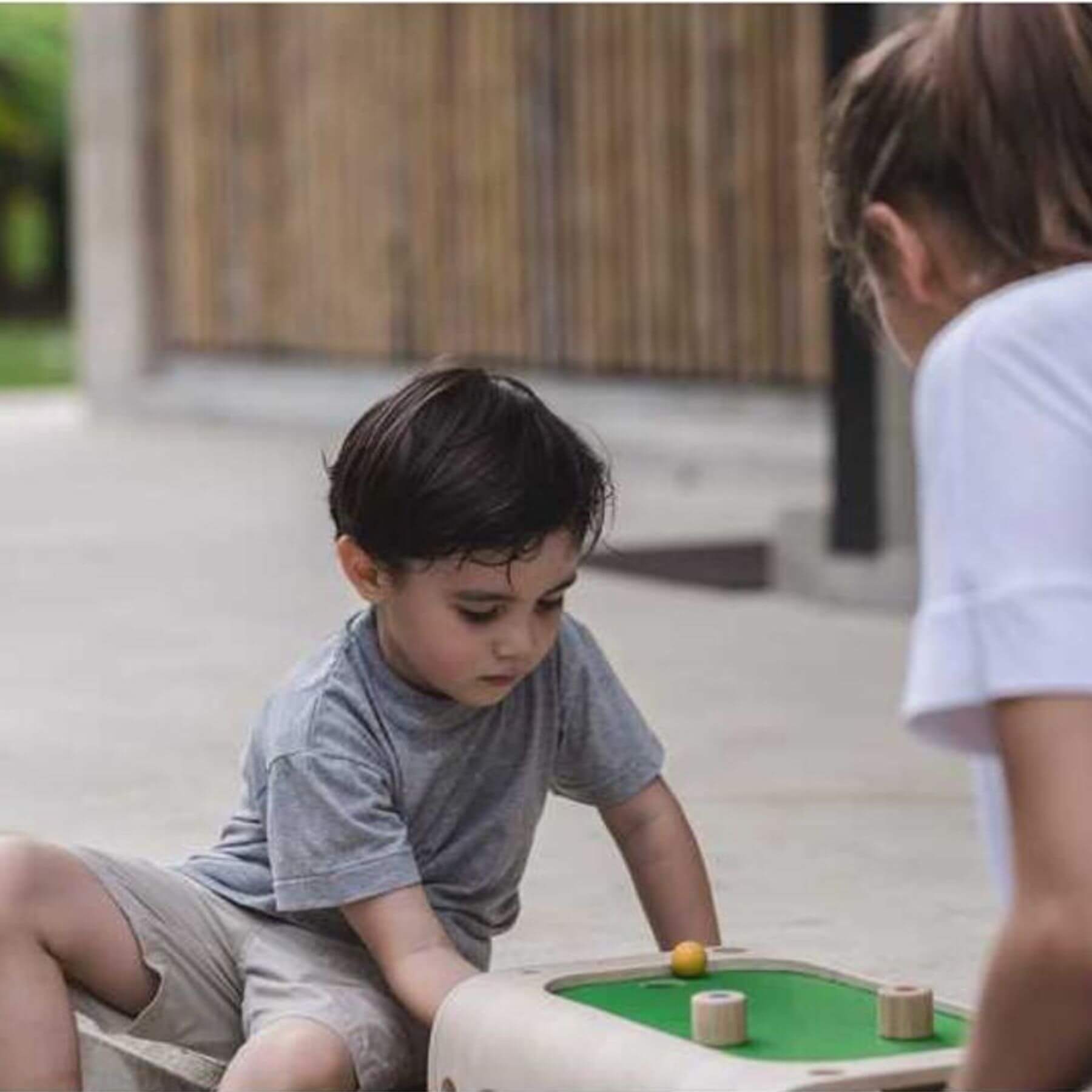 Two children playing with PlanToys Magnetic Board Game on a patio.