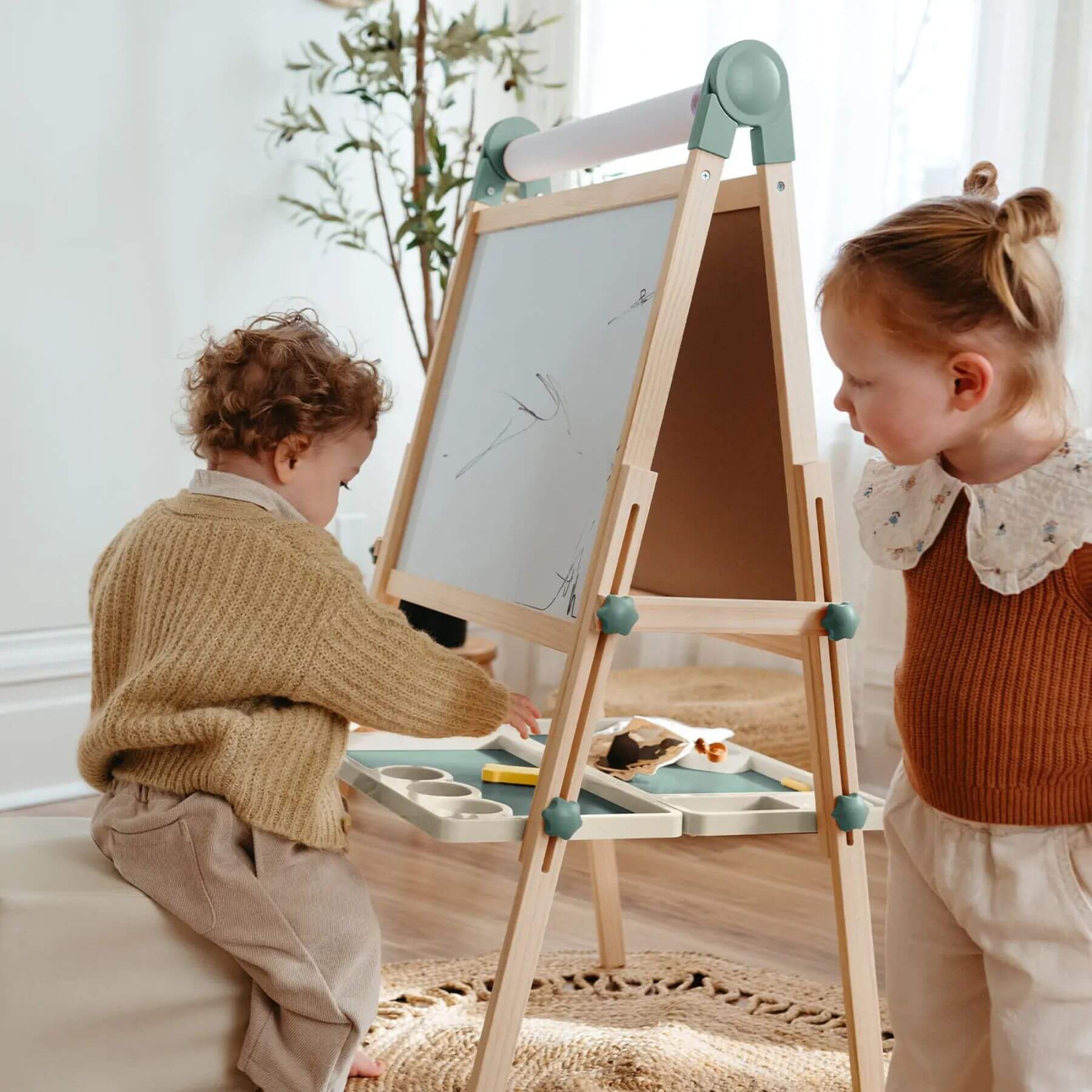 Two children playing with Tiny Land® Magnitales Easel for Kids - Green in a bright room.