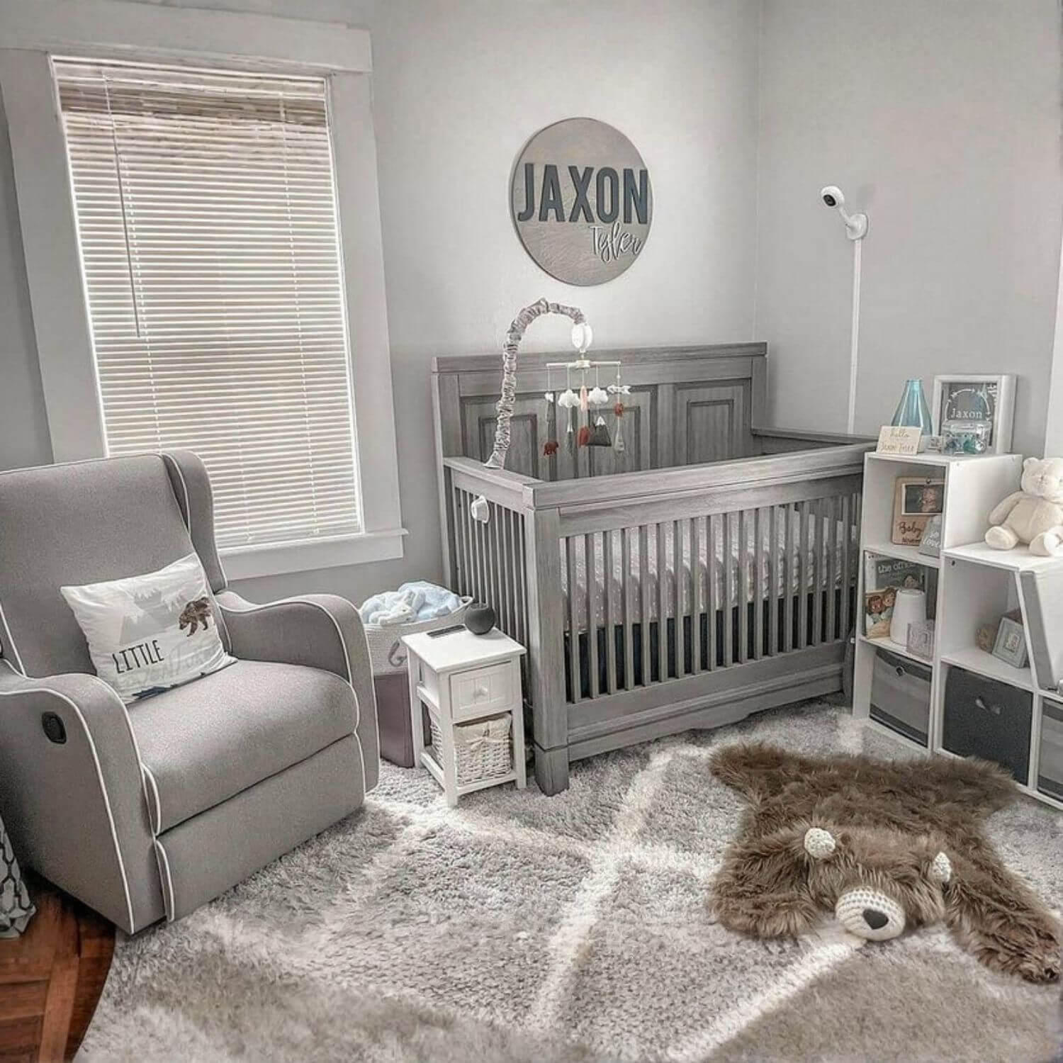 Nursery room with gray crib, armchair, and decor elements.
