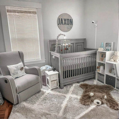 Nursery room with gray crib, armchair, and decor elements.