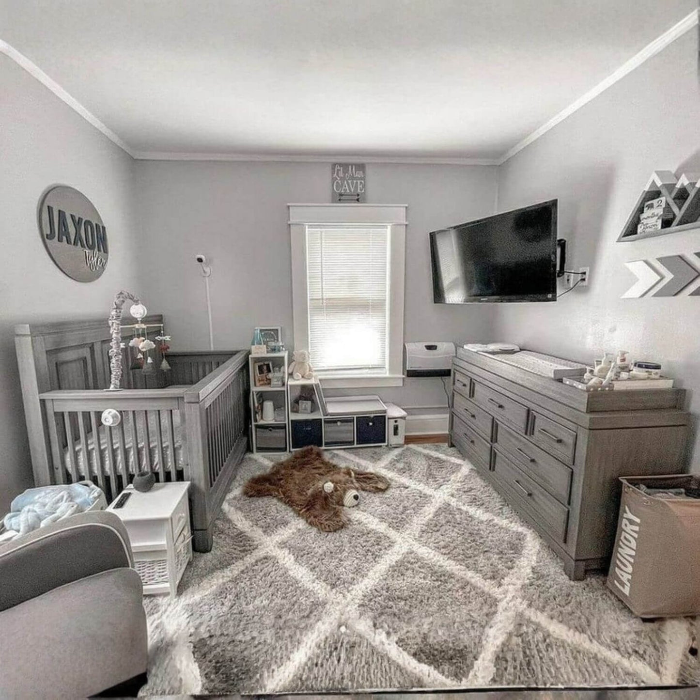 Nursery room with gray crib, dresser, and rug.
