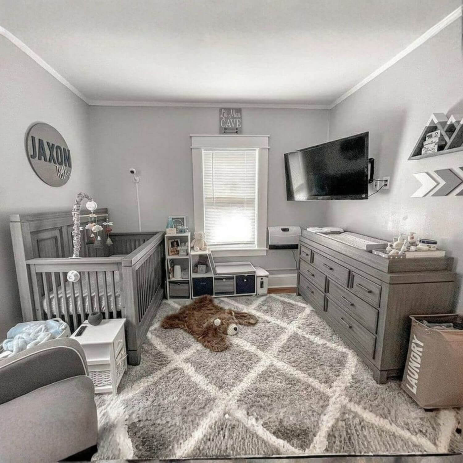 Nursery room with gray crib, dresser, and rug.