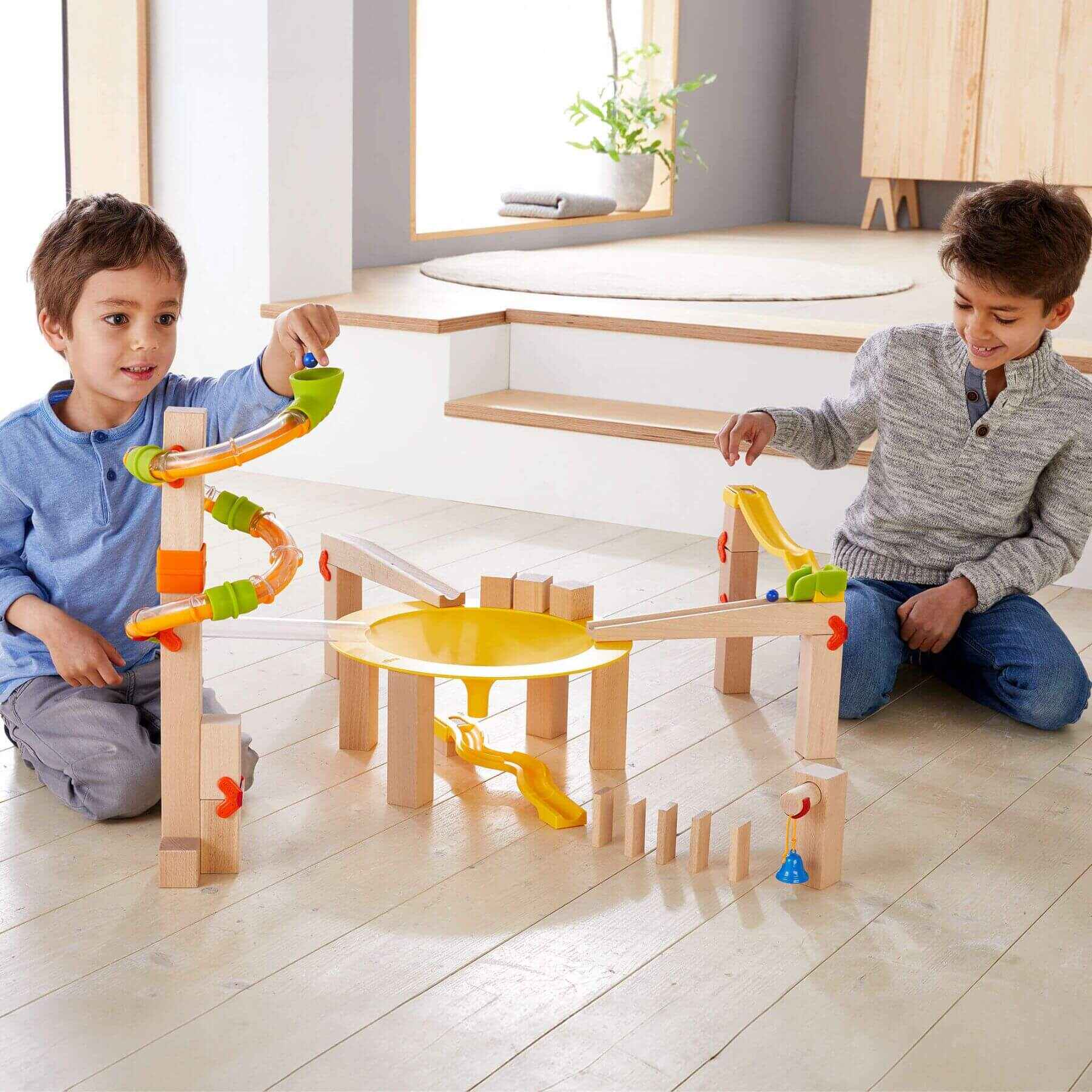 Two children playing with HABA USA Marble Run Funnel Jungle Starter Set in a home setting.