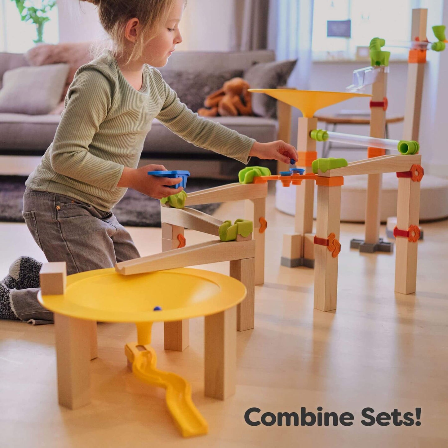 Child playing with HABA USA Marble Run Funnel Jungle Starter Set in a living room.