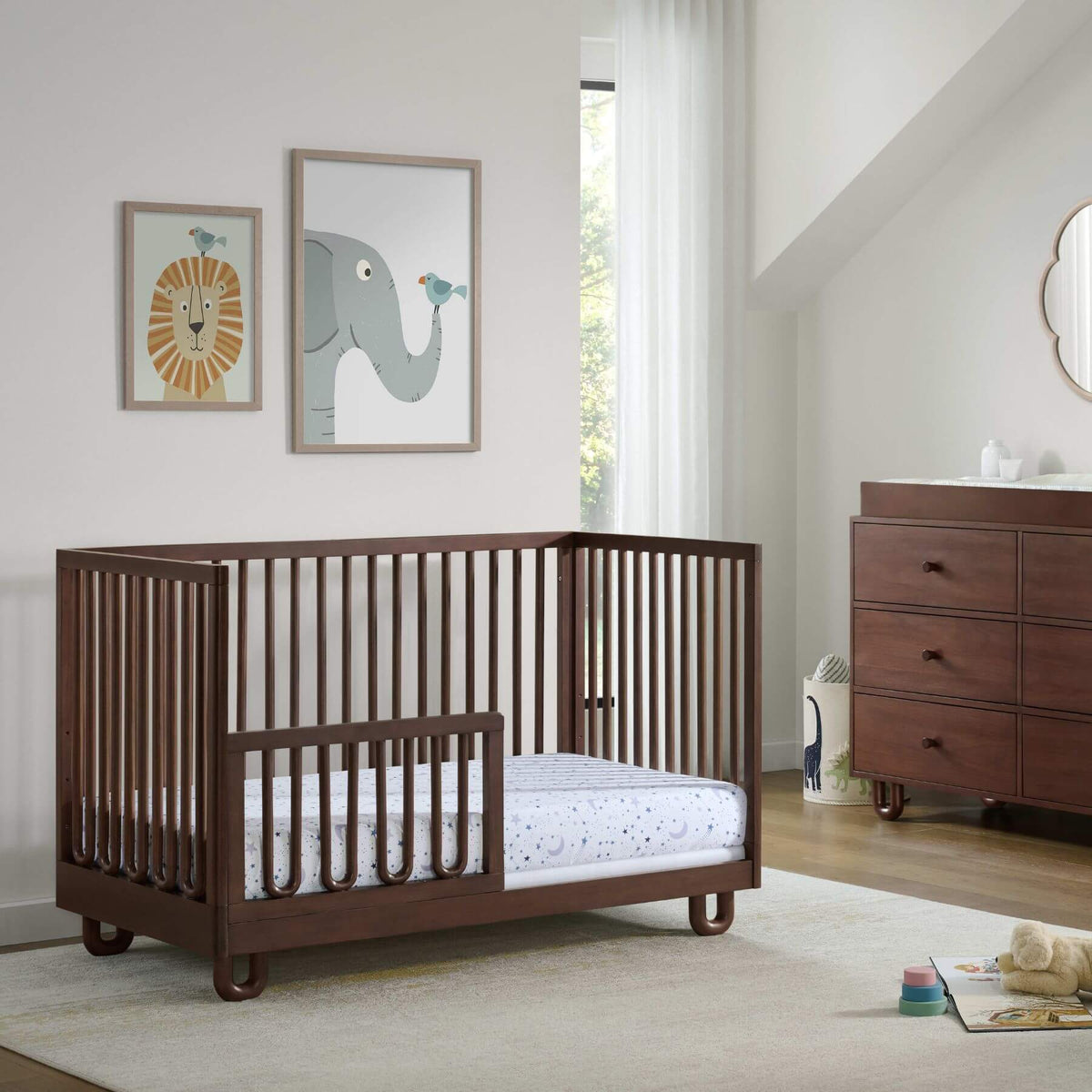 Soho Baby Meridian Island Crib - Cognac in a nursery with a dresser and wall art.