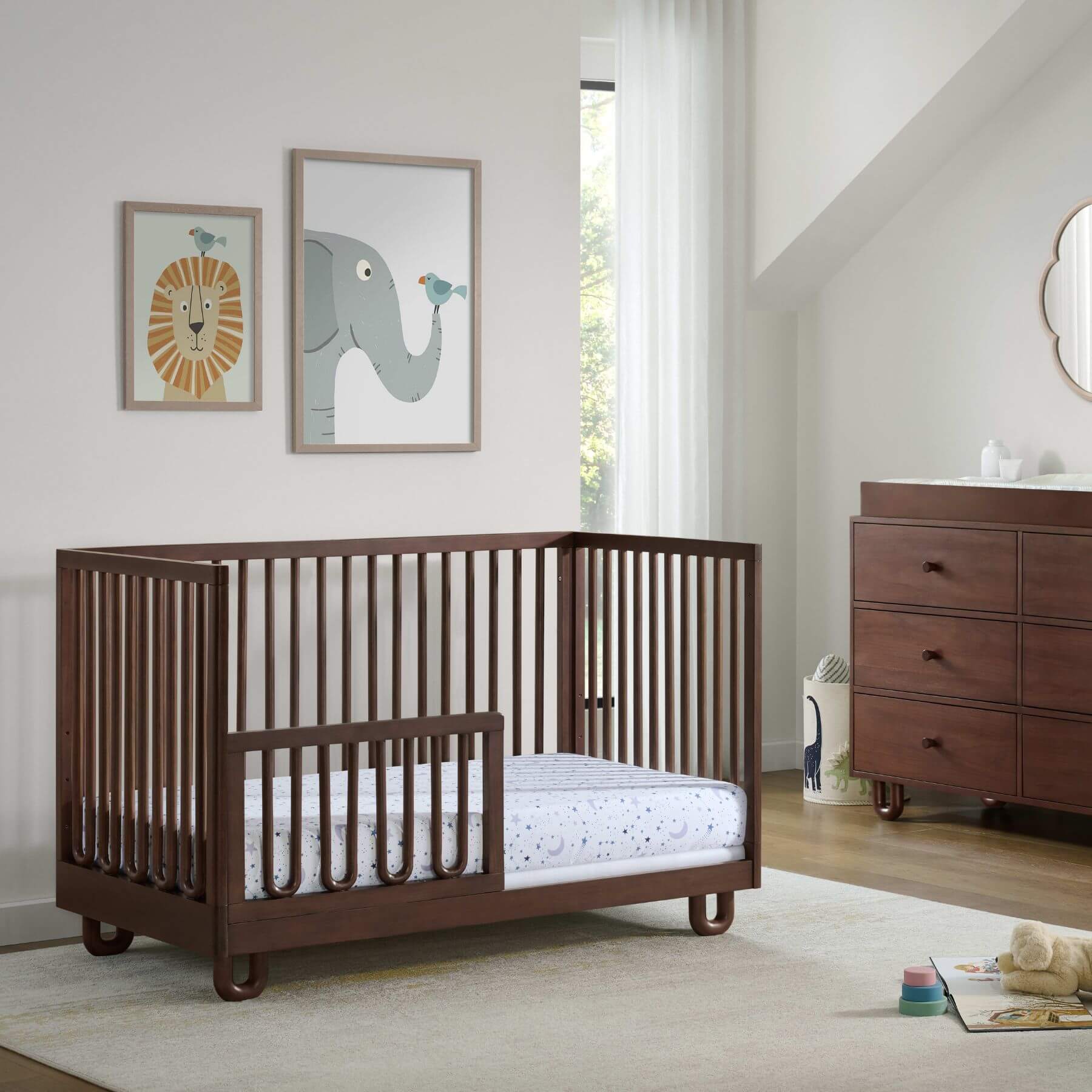 Soho Baby Meridian Island Crib - Cognac in a nursery with a dresser and wall art.