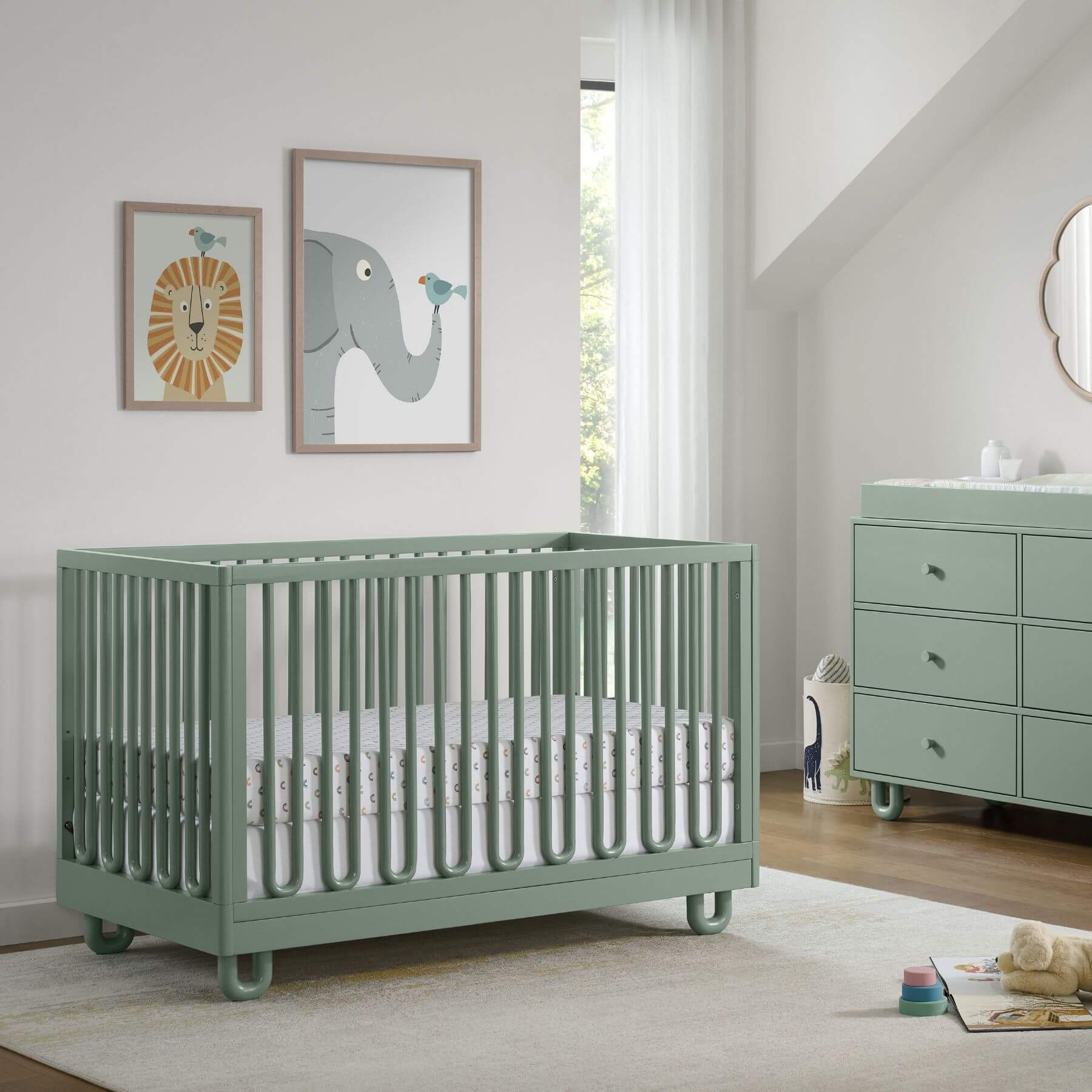Soho Baby Meridian Island Crib - Olive Green is shown in a styled nursery setting next to a matching dresser, with framed animal art on the wall.