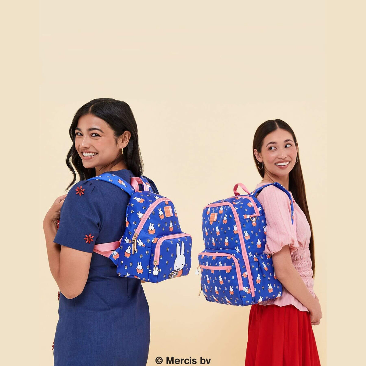 Two young women modeling Miffy Flower Fields Zealous Diaper Bag Backpack - Blue & Orange