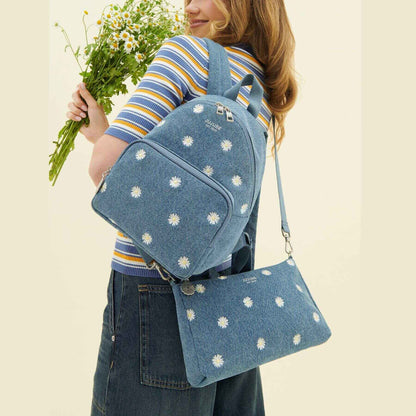 Person wearing JuJuBe Everyday Mini Backpack - Denim & Daisies, holding flowers against a beige background