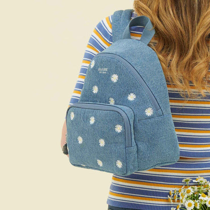 Person wearing JuJuBe Everyday Mini Backpack - Denim & Daisies on a beige background