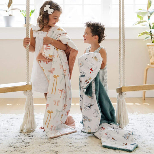 Two children holding Saranoni Minky/Lush Toddler Blankets in a bright, indoor setting.