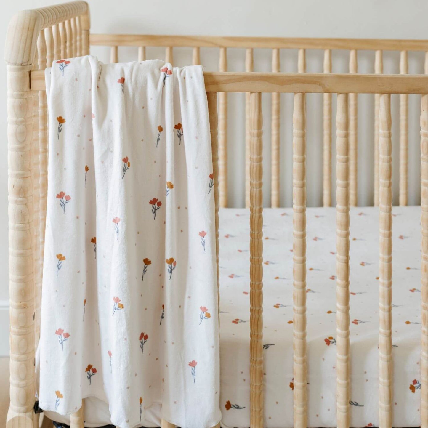Saranoni Minky Stretch Luxe Crib Sheet Coral hanging on wooden crib