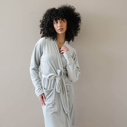 A woman wearing Saranoni Minky Stretch Luxe Robe - Mirage, standing against a plain beige wall.