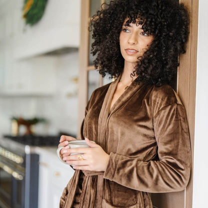 Woman in Saranoni Minky Stretch Luxe Robe - Mocha holding a mug in a kitchen setting