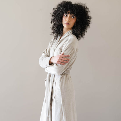 A model with wearing Saranoni Minky Stretch Luxe Robe - Sandshell, standing against a neutral beige background.