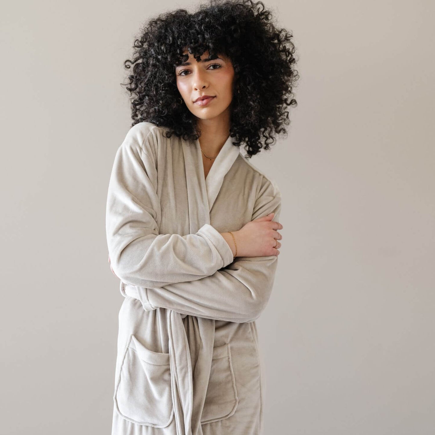 A woman wearing Saranoni Minky Stretch Luxe Robe - Sandshell, standing against a neutral light gray background.