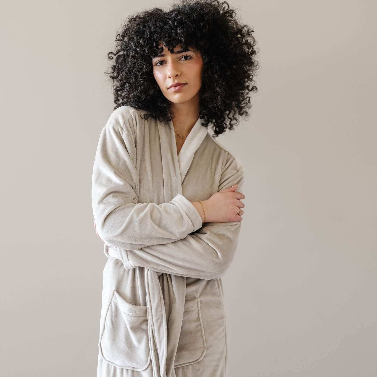 A woman wearing Saranoni Minky Stretch Luxe Robe - Sandshell, standing against a neutral light gray background.