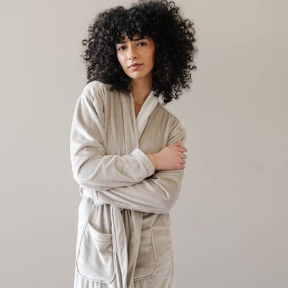 A woman wearing Saranoni Minky Stretch Luxe Robe - Sandshell, standing against a neutral light gray background.