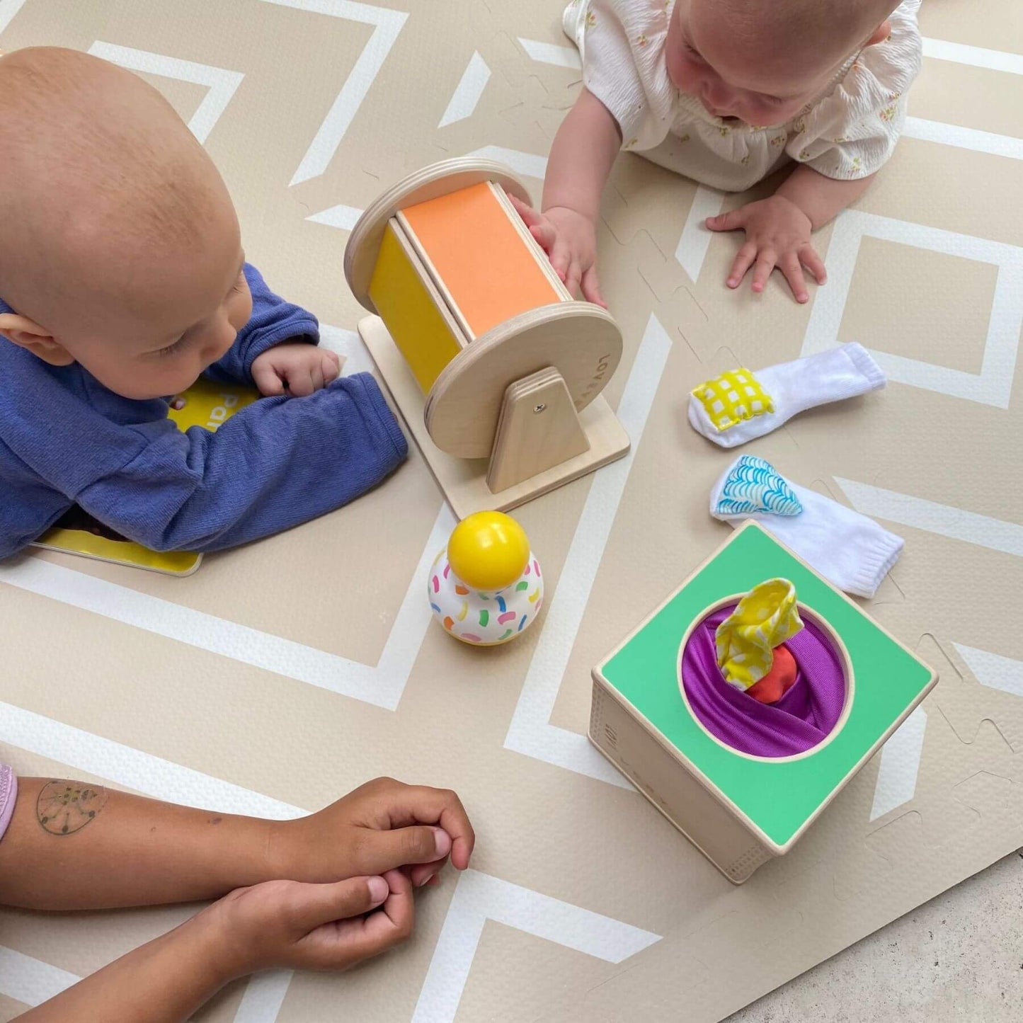 Two babies playing with colorful toys on Eeveve Modern Blocks Play Mat - Beige