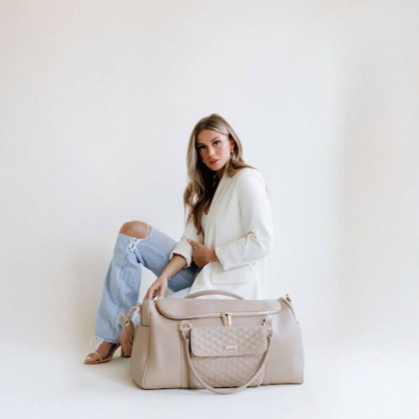 Woman Sitting Behind Luli Bebé Monaco Travel Bag | Latte Brown