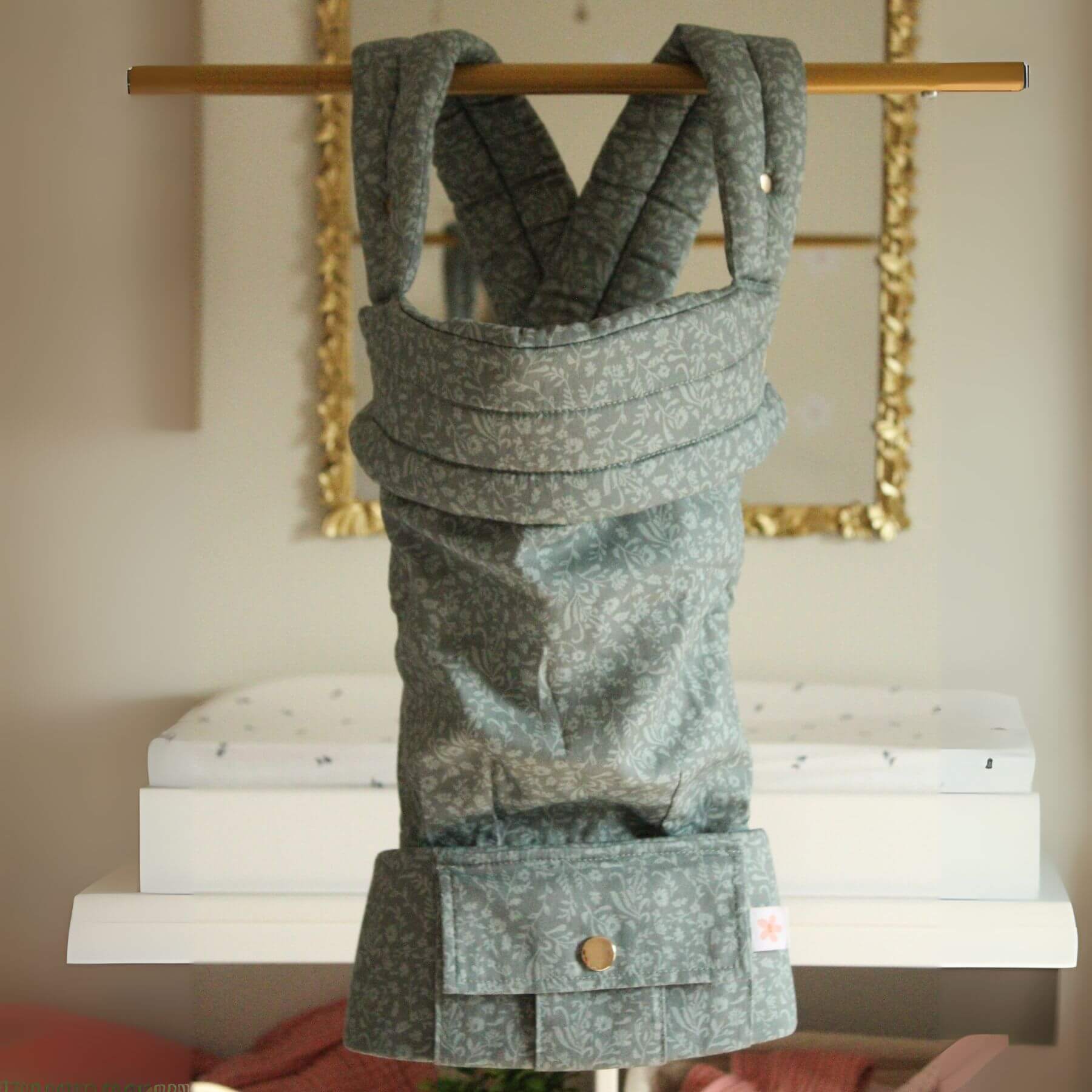 Monroe x Coco Bloom – Neutral Cotton Baby Carrier on a wooden stand with a neutral background