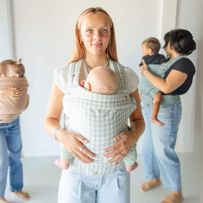 Two women holding babies in Monroe x Coco Gingham - Cotton Baby Carriers against a white background