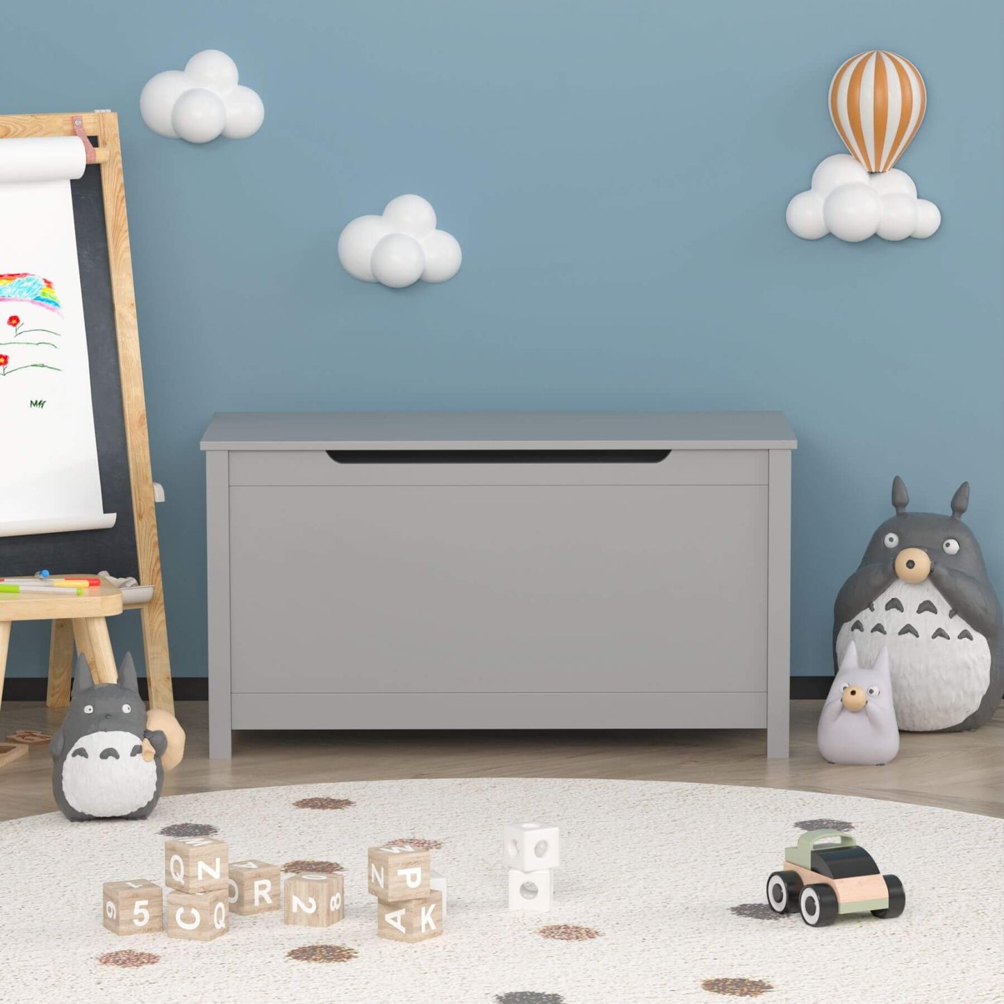 Children's playroom with MOONRIVER Kids Wooden Toy Box Storage with Safety Hinged Lid - Grey and toys on a light blue wall.