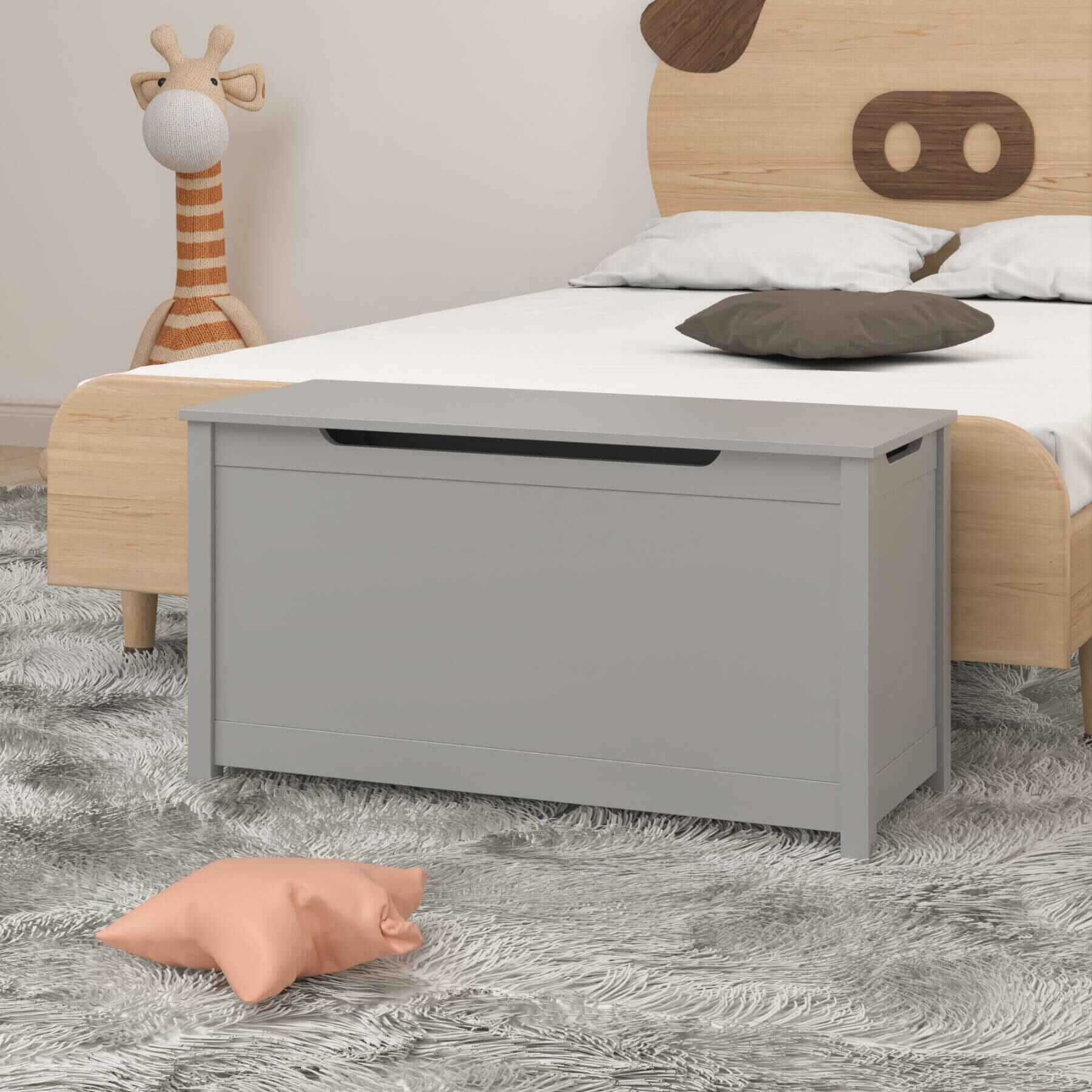 Children's bed with wooden headboard and MOONRIVER Kids Wooden Toy Box Storage with Safety Hinged Lid - Grey on a gray carpet.