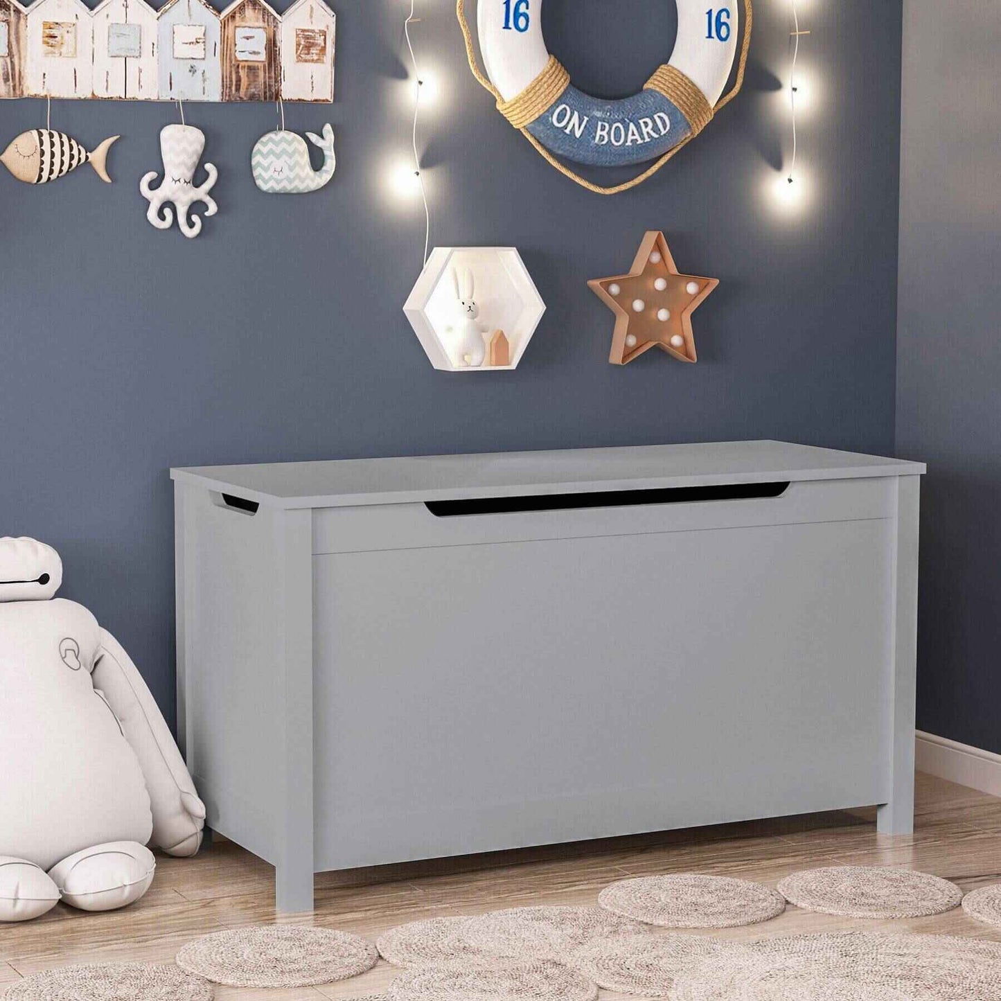 MOONRIVER Kids Wooden Toy Box Storage with Safety Hinged Lid - Grey against a blue wall with decorative items in a room.