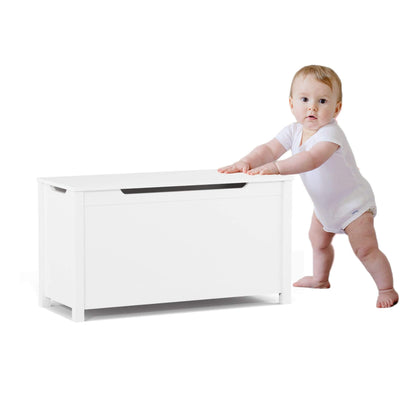 Baby in a white onesie standing next to MOONRIVER Kids Wooden Toy Box Storage with Safety Hinged Lid - White