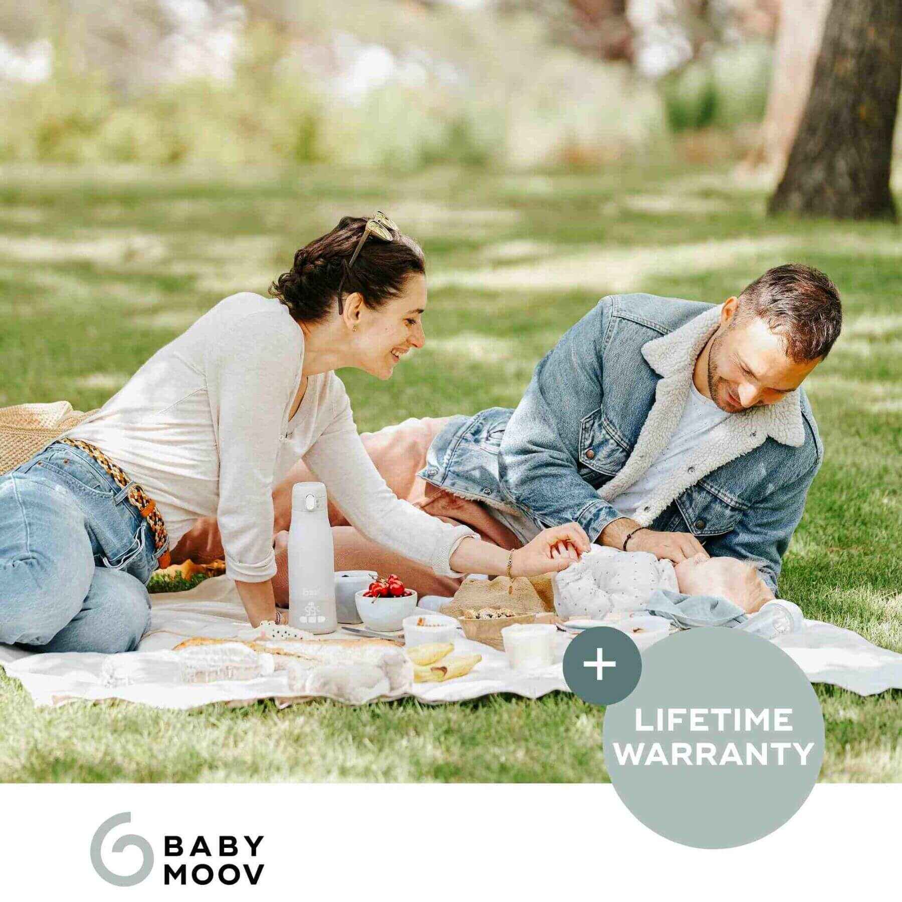 Couple having a picnic in a park with Moov & Feed Portable Milk and Water Warmer and food