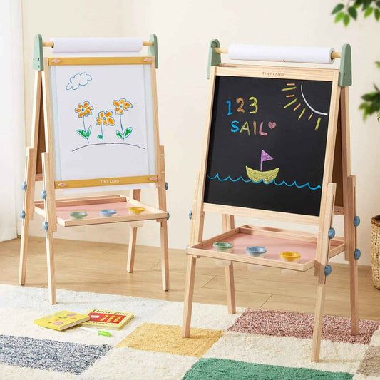 Double-sided children's easel with whiteboard and blackboard, featuring drawings and writings on a wooden floor.