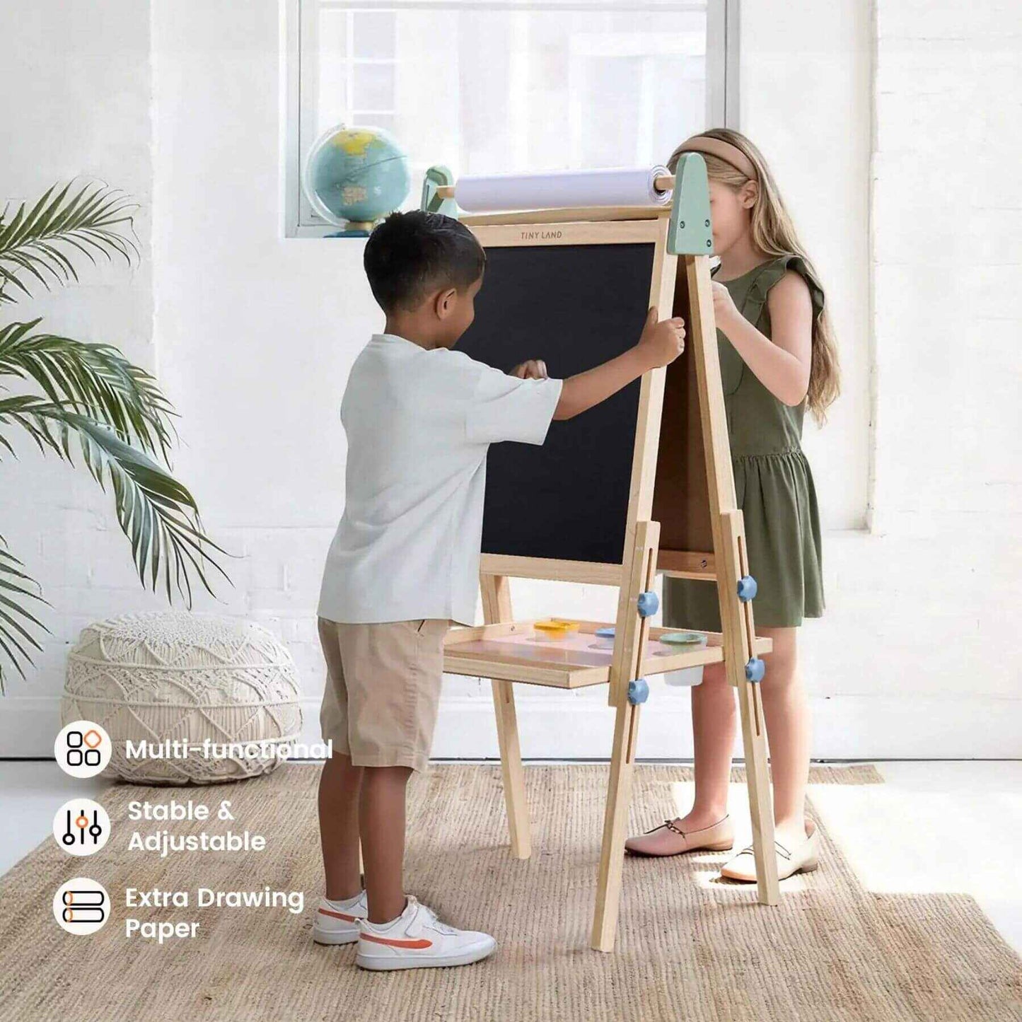 Two children using a multi-functional adjustable easel in a bright room.