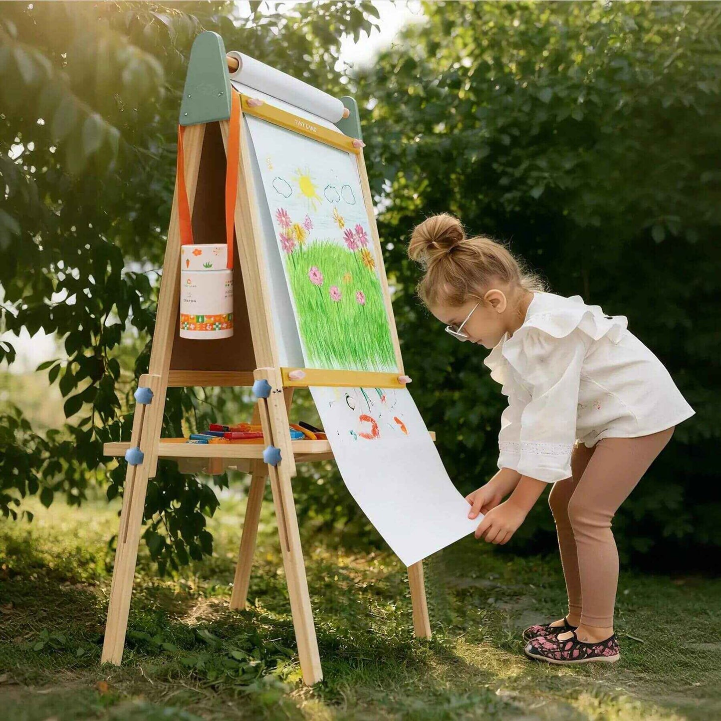 Child drawing on an outdoor easel with nature in the background