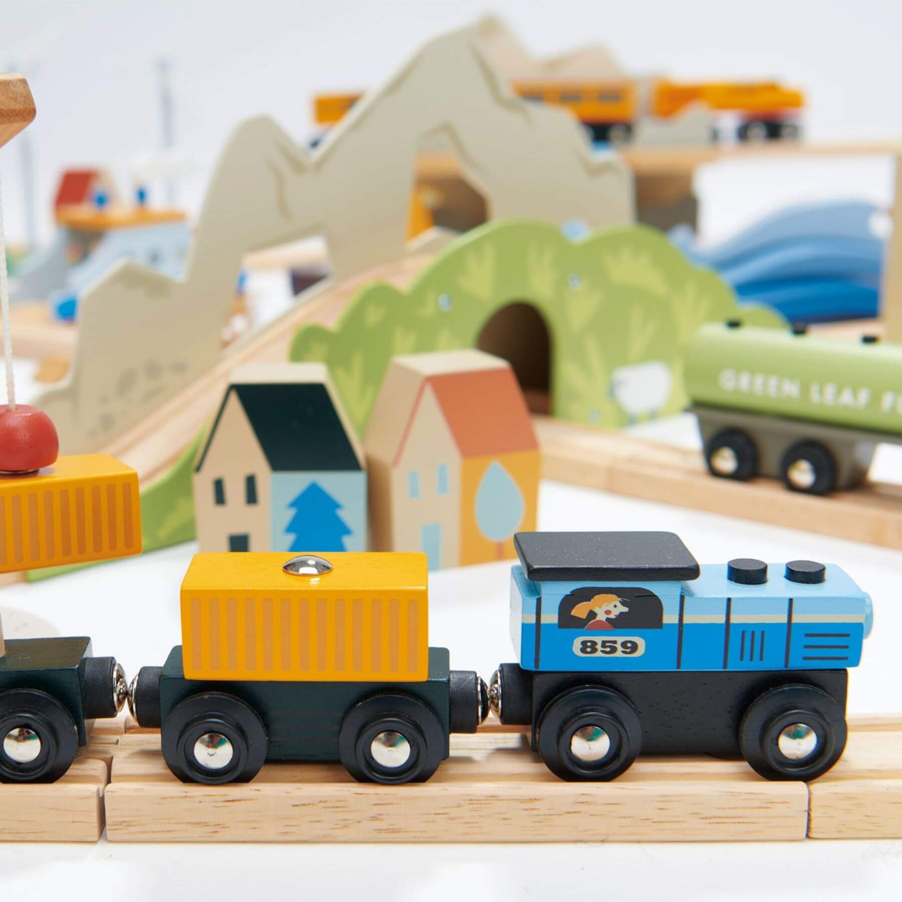 Wooden toy train set on a track with a scenic background