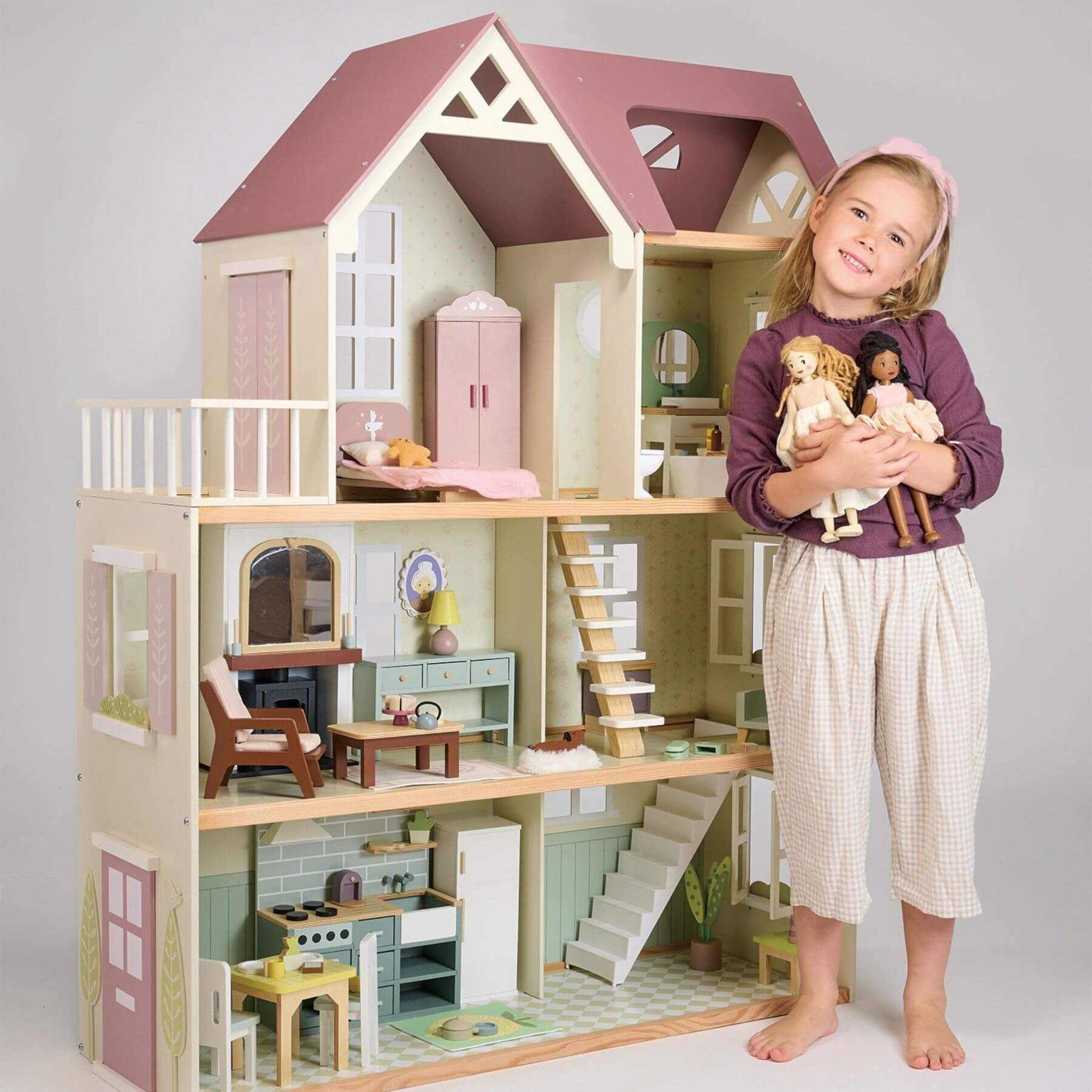 Child holding dolls next to Tender Leaf Mulberry Mansion with detailed interior.