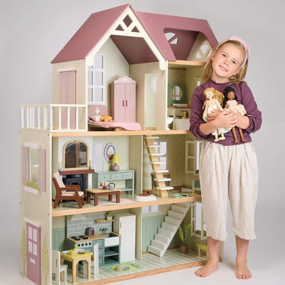 Child holding dolls next to Tender Leaf Mulberry Mansion with detailed interior.