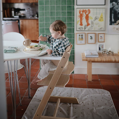 Child sitting on a high chair at a table in a kitchen