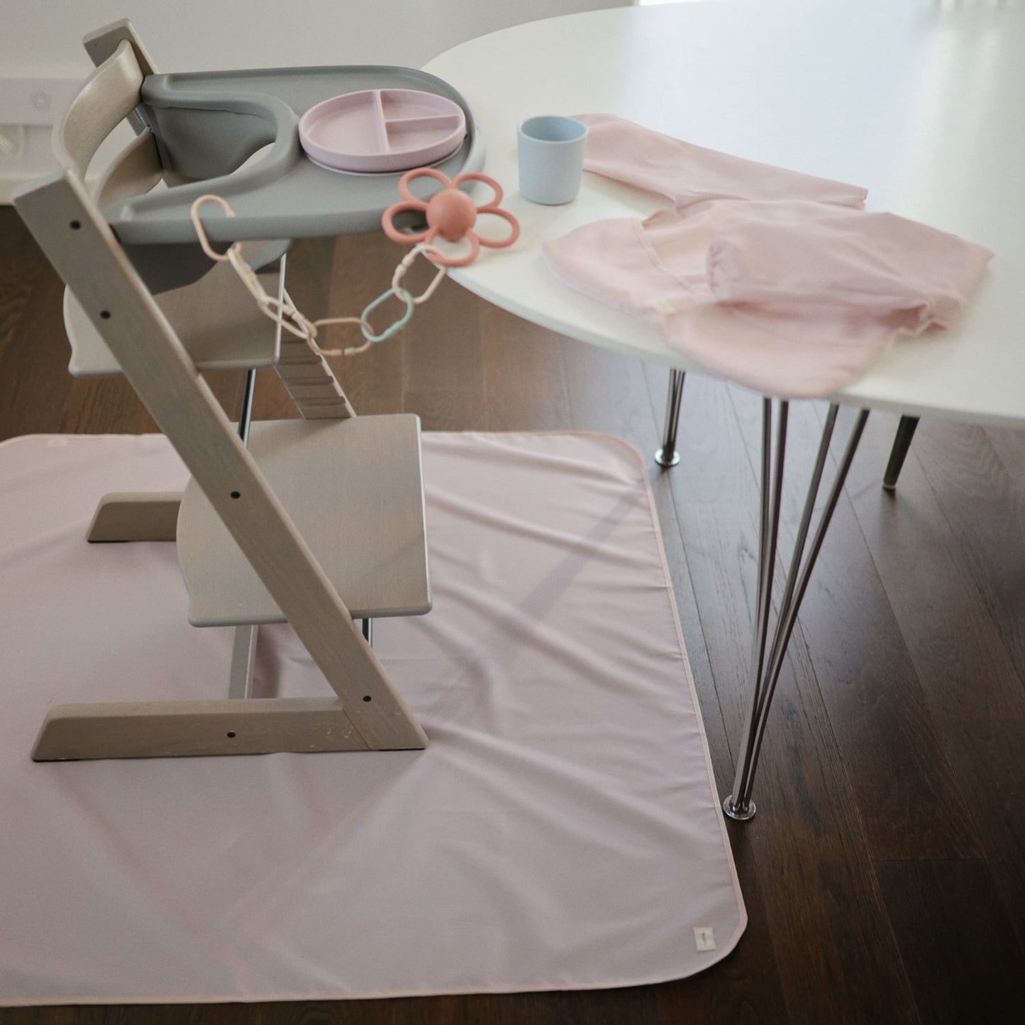 Children's high chair with accessories on a white table and floor.