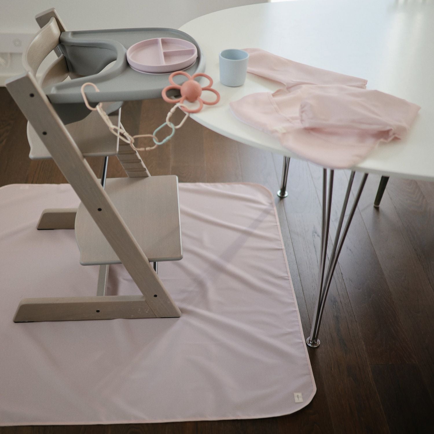 Children's high chair with accessories on a white table and floor.