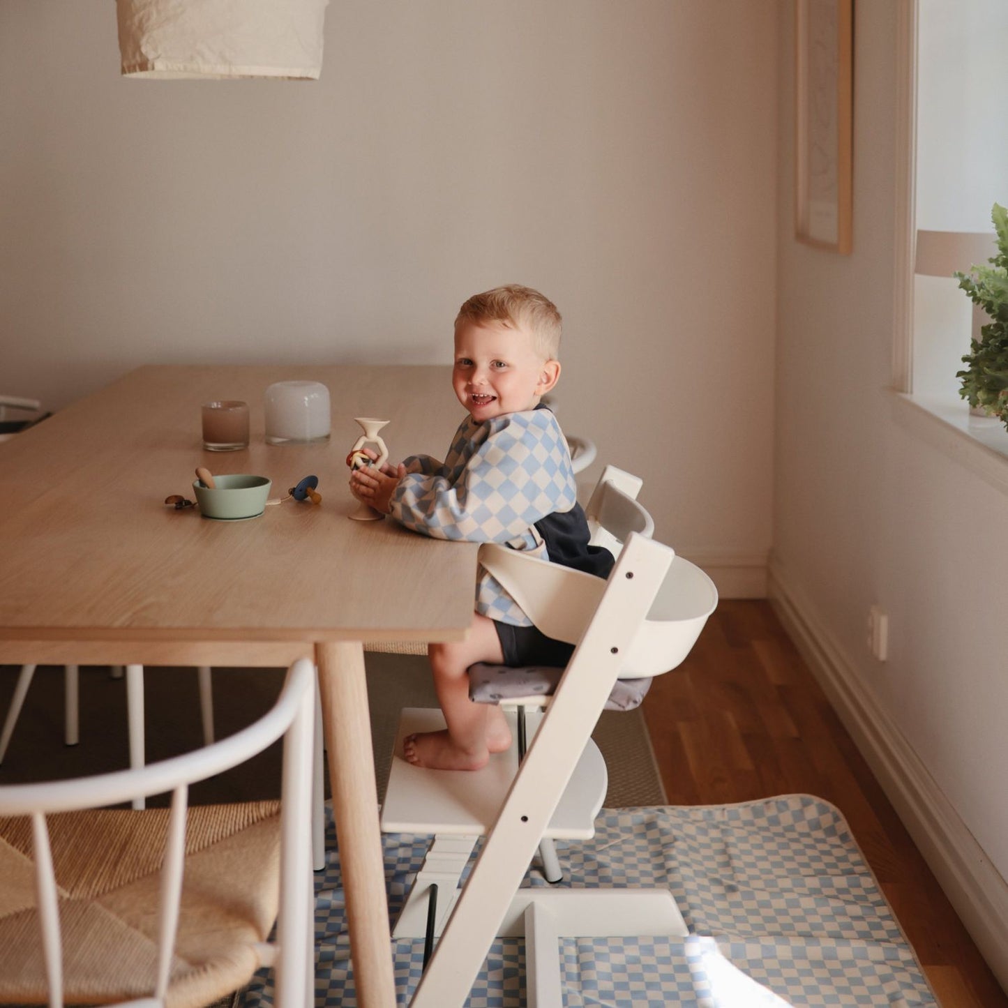 Child sitting in a high chair at a dining table in a home setting