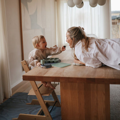 Woman and child at a wooden table in a bright room