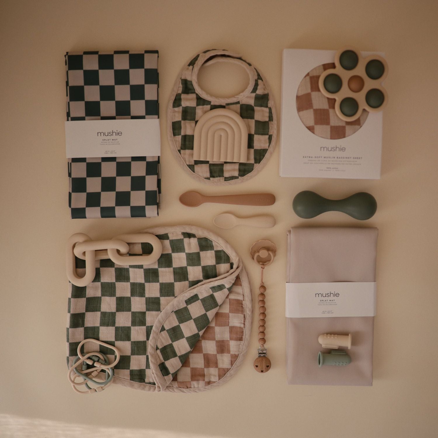 Collection of baby toys and items on a beige surface with 'mushie' branding.