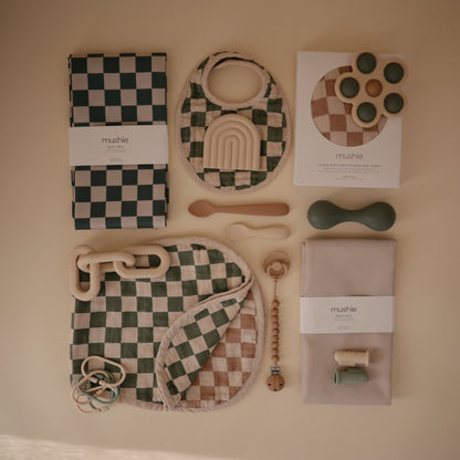 Collection of baby toys and items on a beige surface with 'mushie' branding.
