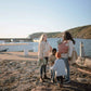 Family of four standing on a rocky dock by the water with boats in the background.