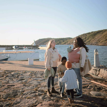 Family of four standing on a rocky dock by the water with boats in the background.