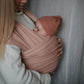 Person holding a baby wrapped in Mushie Baby Wrap against a neutral background