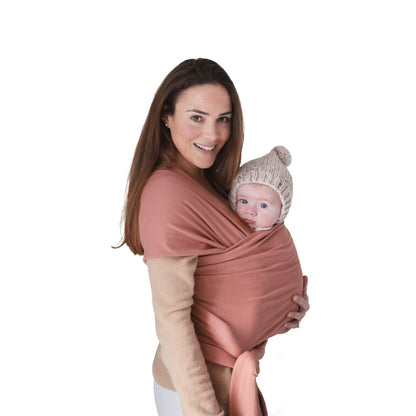 Woman holding a baby in Mushie Baby Wrap Cedar against a white background