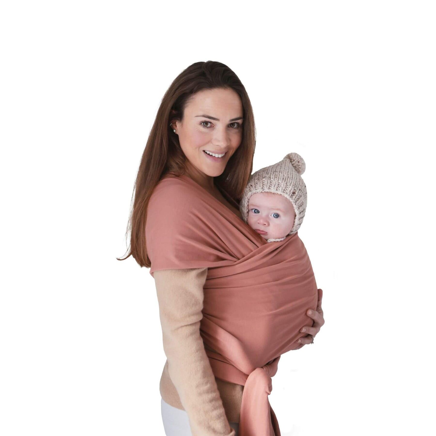 Woman holding a baby in Mushie Baby Wrap Cedar against a white background
