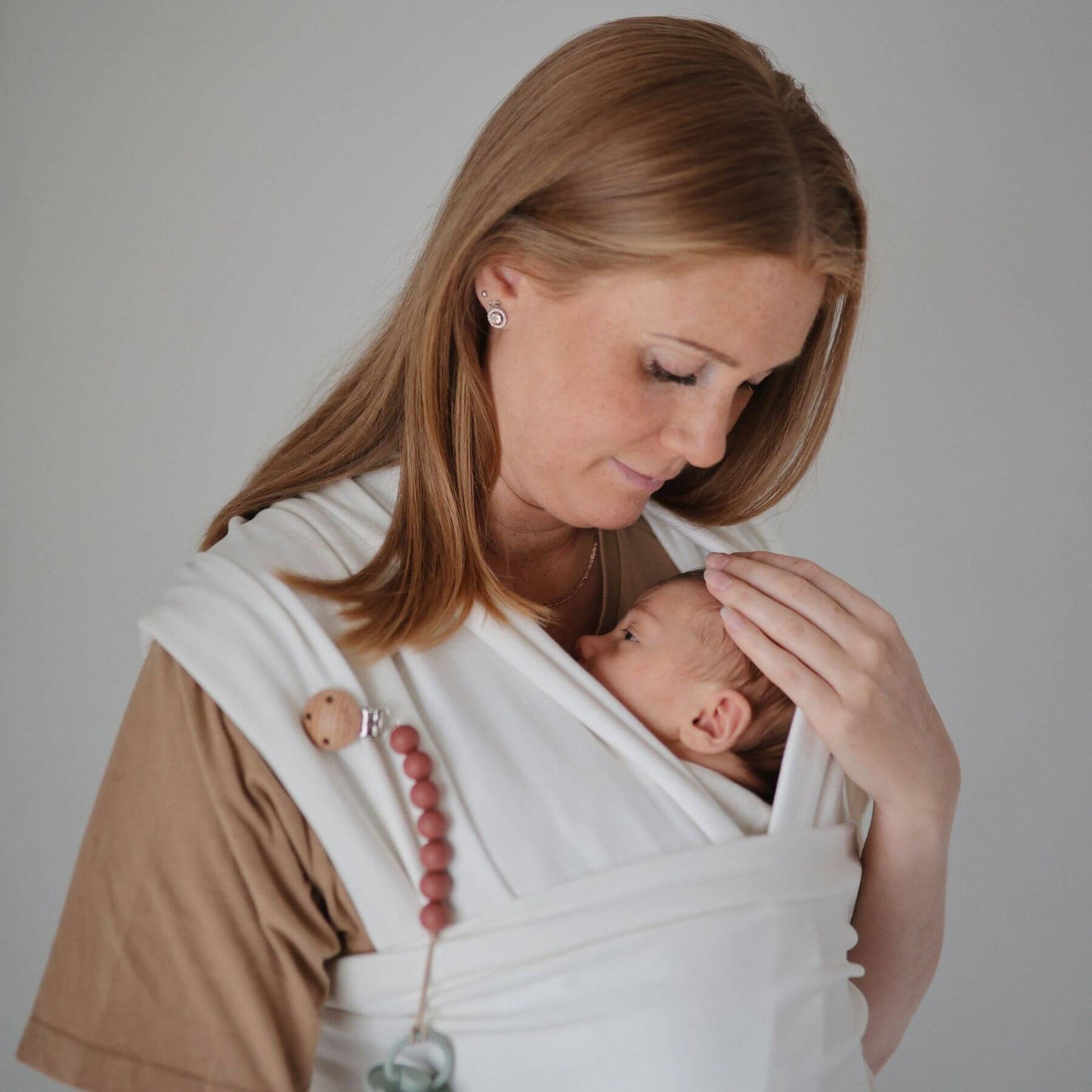 Woman holding a baby in Mushie Baby Wrap Ivory
